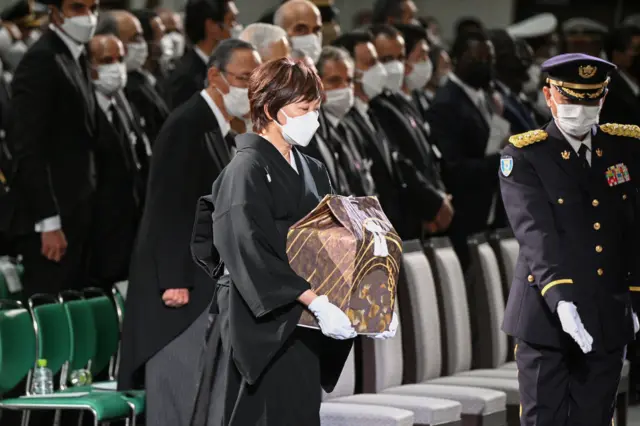 The widow of former Japanese prime minister Shinzo Abe, Akie Abe (C), carries his ashes as she arrives for the start of his state funeral at the Nippon Budokan in Tokyo on September 27, 2022.