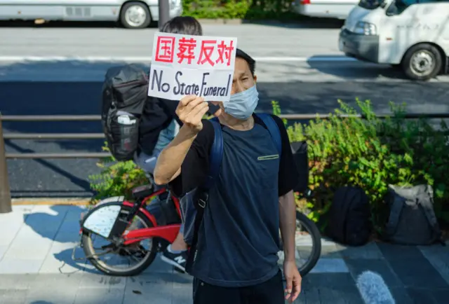 A protester holds a placard against the state funeral of former Japanese prime minister Shinzo Abe outside the Nippon Budokan in Tokyo on September 27, 2022. -