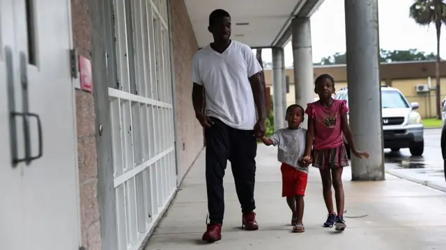 A man brings children to a shelter for evacuees ahead of Hurricane Ian at Lockhart Elementary school in Tampa, Florida, U.S., September 28, 2022. REUTERS/Shannon Stapleton