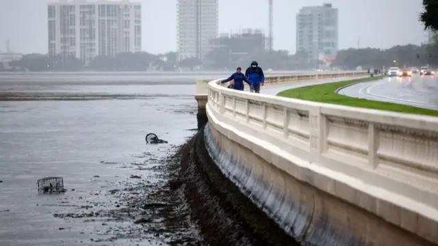 People walk along the shore of Tampa Bay's Bayshore Boulevard on Wednesday morning