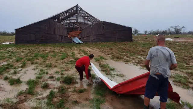 Two men work to restore a damaged tobacco warehouse in Pinar del Rio, Cuba