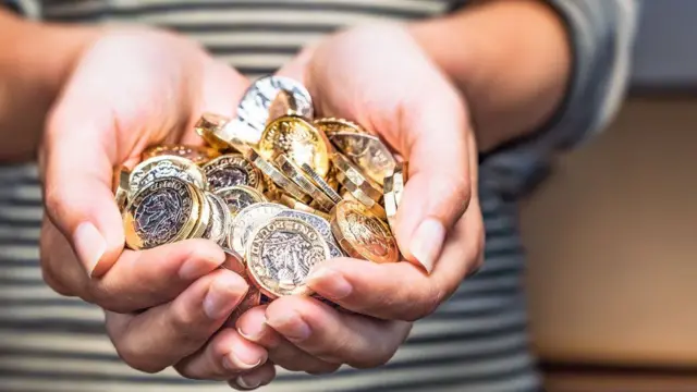 Person holding pound coins in their hands