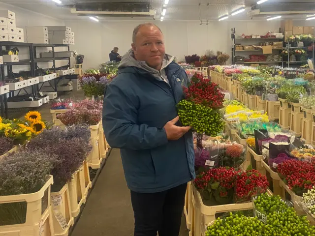 Jeff Large poses with bouquets of flowers