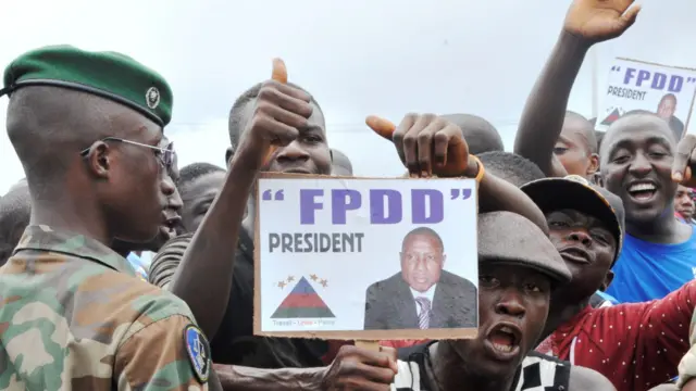 Supporters of Guinea's exiled former junta chief Moussa Dadis Camara demonstrate in front of soldiers, on August 26, 2015 at the airport in Conakry.