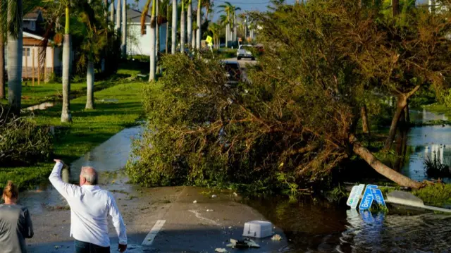 People walk down a flooded road in Punta Gorda, Florida