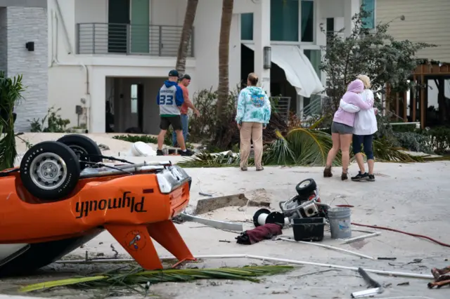 People embrace as they survey property damage from Hurricane Ian on September 29, 2022 in Bonita Springs, Florida.