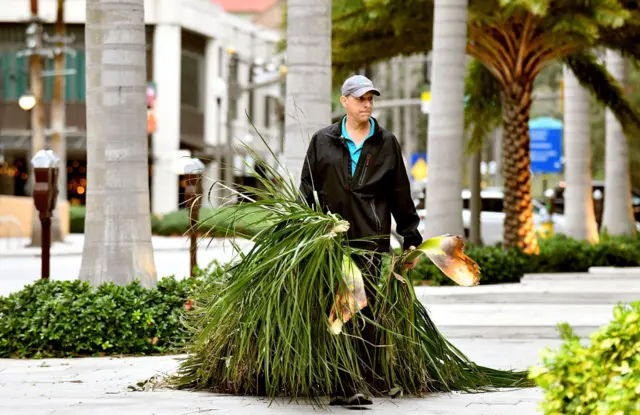 A local resident cleans debris in downtown Saint Petersburg after Hurricane Ian passed through the area on 29 September 2022 in Saint Petersburg, Florida