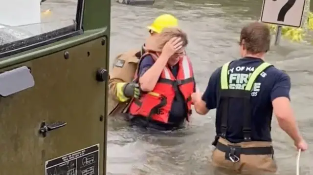 Firefighters rescue a woman from a car trapped in water in Naples