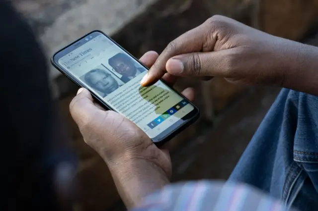 A man looks at his smartphone in Kigali, Rwanda, on May 18, 2020, showing the article on The New Times of the arrest of Felicien Kabuga