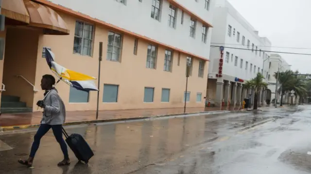 A man clutches a broken umbrella in Hurricane Ian