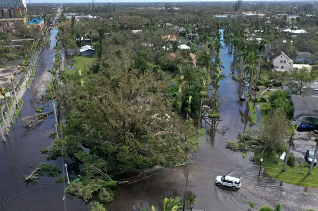 Vehicles make their way through a flooded area in Fort Myers, Florida