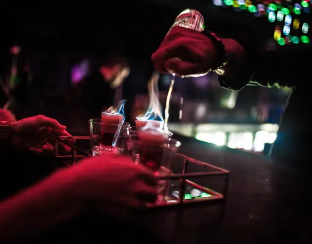 Close-up of hand preparing drink at bar counter (stock photo)