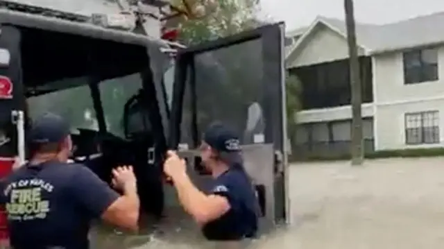 Firefighters by open door or half-submerged fire engine