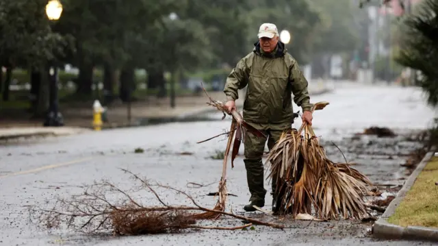 A local resident hauls debris from the road