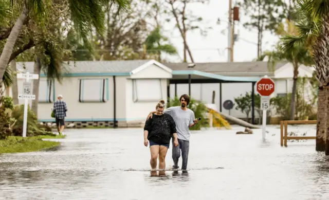 People walk through a flooded neighbourhood in the wake of Hurricane Ian in Fort Myers, Florida