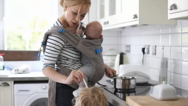 A woman feeds her child as she cooks food