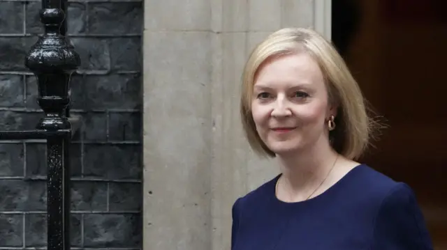 Prime Minister Liz Truss leaves Downing Street. She is wearing a navy blue dress.