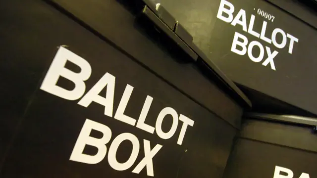 Black ballot boxes piled up in a polling station