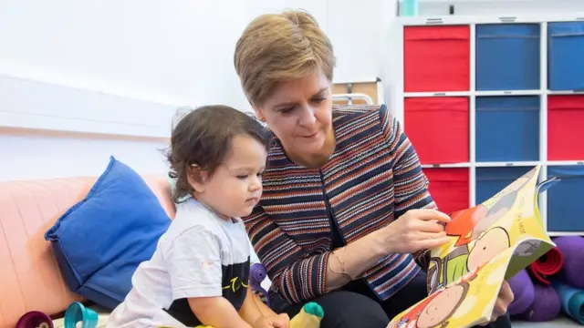 Nicola Sturgeon reads a book with a small child