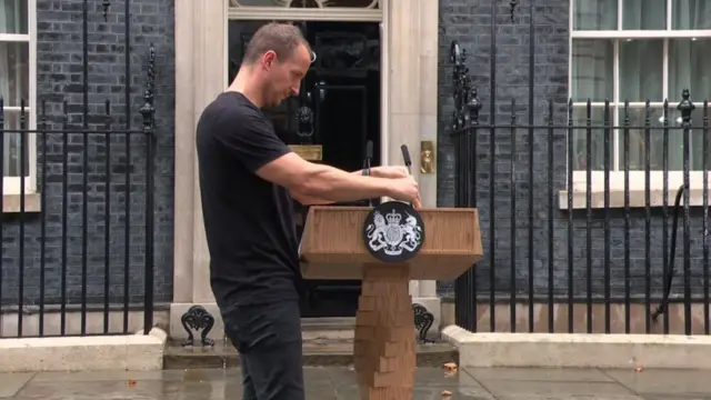 Downing Street staff adjust the lectern microphone