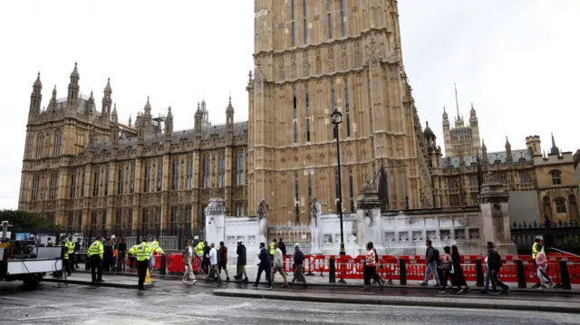 Police officers stand guard during a clean up operation after Animal Rebellion activists threw paint on the walls and road outside the Houses of Parliament