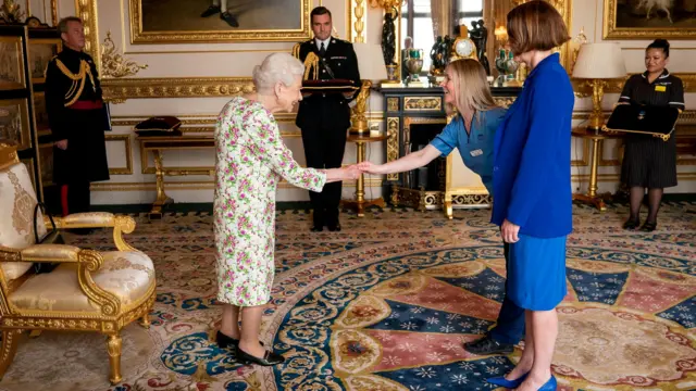 Queen Elizabeth shakes hands with representatives of the National Health Service