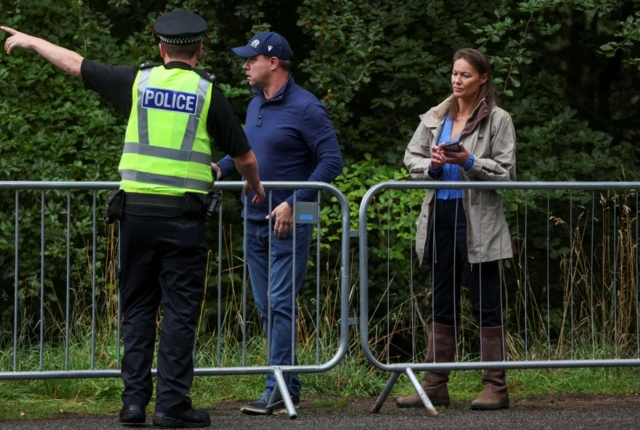 Police officer points people behind barriers outside Balmoral Castle