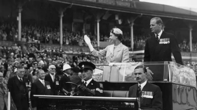 Queen Elizabeth II and Prince Philip wave to crowds as they are driven on a circuit of Melbourne Cricket Ground as part of their Australian tour