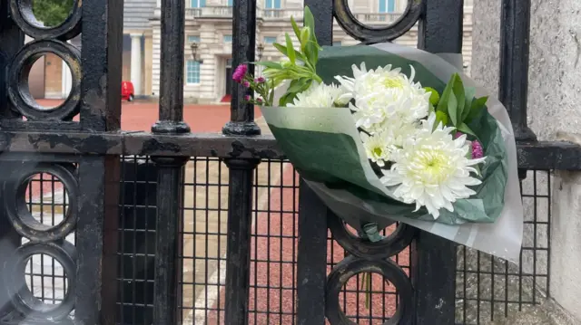 A bunch of flowers tied to the gates of Buckingham Palace