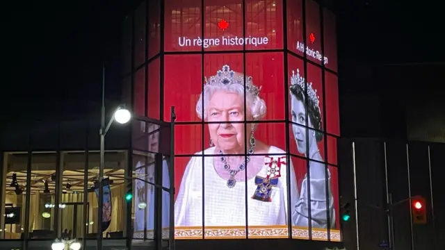 a huge picture of the Queen lights up the side of the National Arts Centre