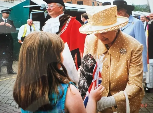 Lily Yorke aged 8 meeting the Queen, who is wearing a yellow polka dot jacket and yellow and white hat