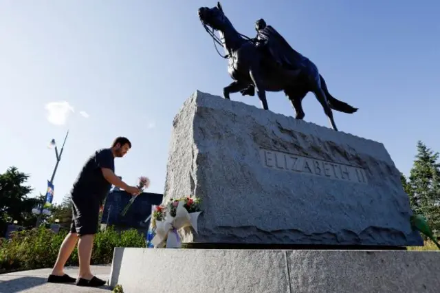 Ryan Furlong brings flowers to a statue of Queen Elizabeth II near Rideau Hall, after Queen Elizabeth, Britain's longest-reigning monarch and the nation's figurehead for seven decades, died aged 96, in Ottawa, Ontario, Canada,