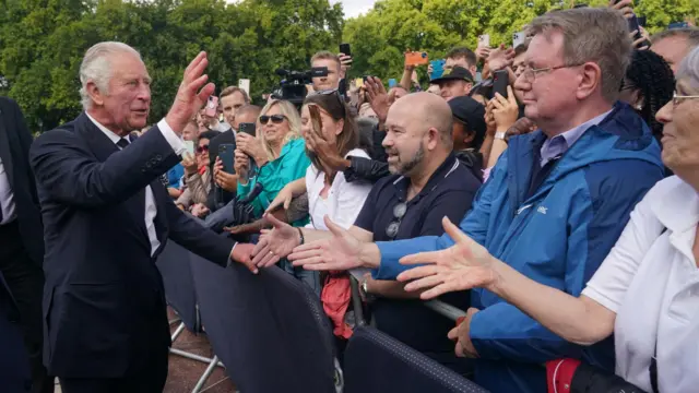 King Charles III is greeted by well-wishers during a walkabout to view tributes left outside Buckingham Palace