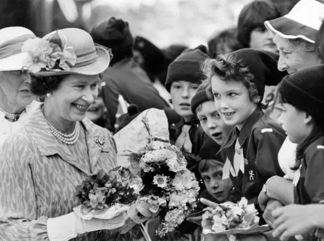 Jo Woodley, from the Wirral, gives a rose to a smiling Queen