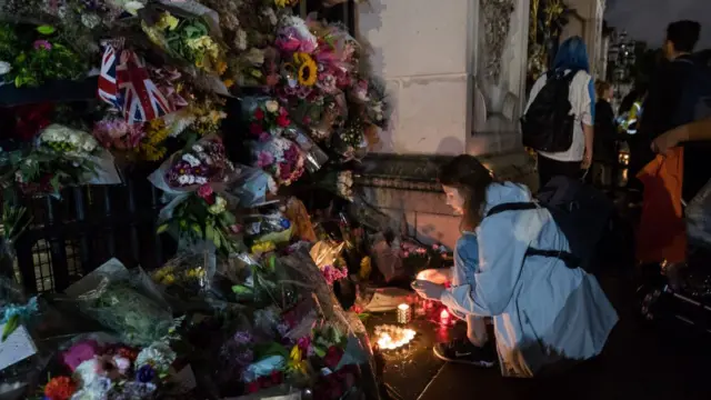 A woman arranges candles into a shape of a heart outside Buckingham Palace following the announcement of the death of Queen Elizabeth II in London, United Kingdom on September 08, 2022.