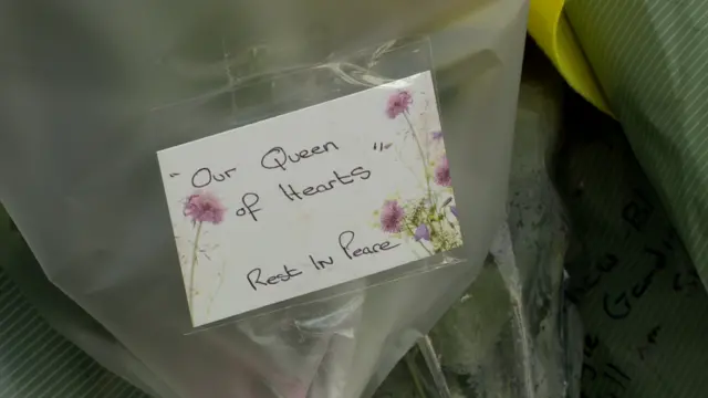 A floral bouquet with the sign 'Our Queen of Hearts. Rest in Peace'