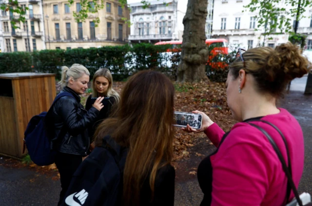 Four women watch the new King's speech on their mobile phones