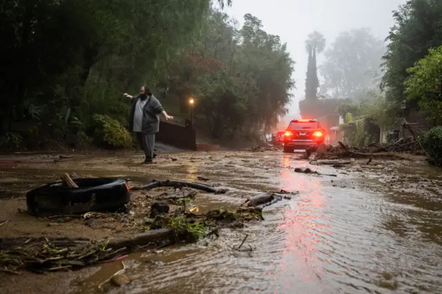 A resident attempts to help a vehicle stuck on Fredonia Drive in Studio City where a mudslide is blocking the road