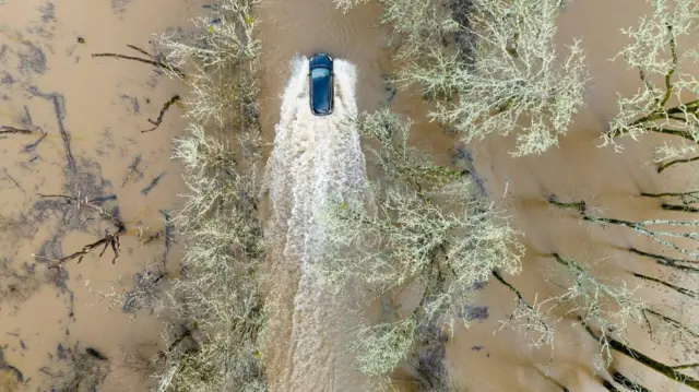 A vehicle drives on a flooded road in Sebastopol, California, on January 5, 2023. - Excessive rain, heavy snow and landslides are expected to wallop California through Thursday as a series of winter storms rip across the western US coast, prompting Governor Gavin Newsom to declare a state of emergency.