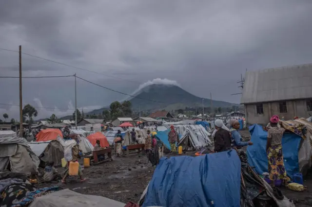 Displaced people walk around their shelters looking for food for their families in Kanyaruchinya on December 5, 2022