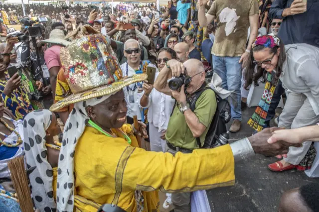 The traditional leader of the Voodoo cult, His majesty Daagbo Hounon Houna II (L), greets the crowd as a touris