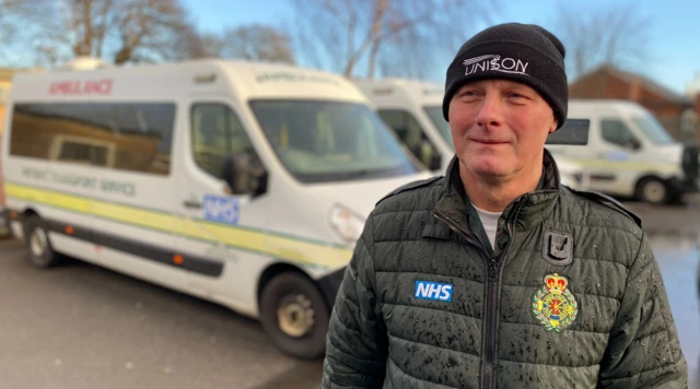 Kevin Haynes, in uniform standing in front of a patient transport vehicle