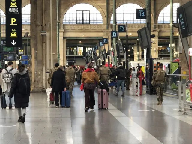 Passengers are seen waiting at the Gare du Nord train station as French police cordon off an area after a knife-wielding suspect injured six people, including a police officer in Paris,