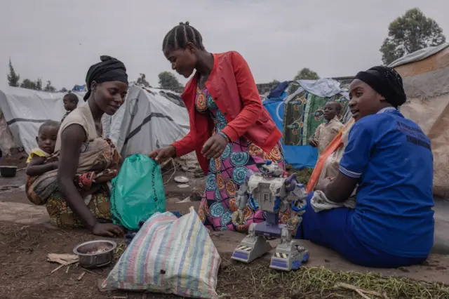 Families displaced by the M23 conflict crisis open Christmas presents with their children during an activity organised by the Un Jour Nouveau organisation in Kanyarushinya in the north of Goma city on December 24, 2022.