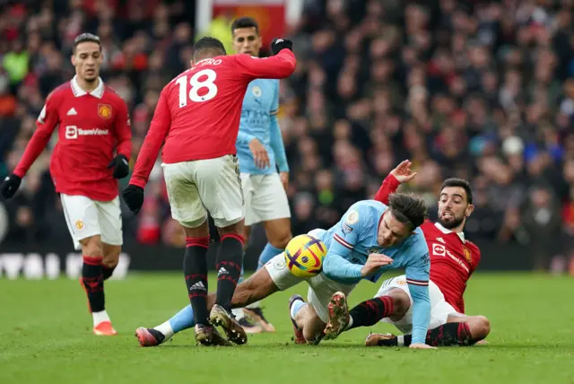 Man City forward Jack Grealish is challenged by several Man Utd players.