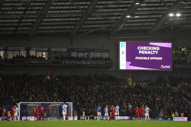 Players of both sides await the decision of the Video Assistant Referee.