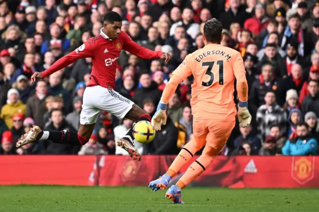 Man City keeper Ederson rushes out of his goal to challenge Man Utd's Marcus Rashford.