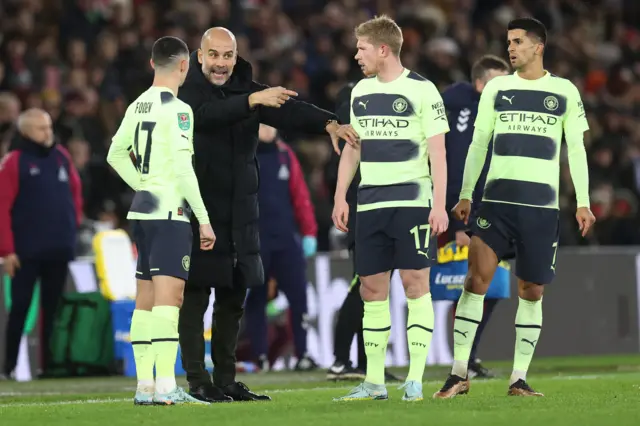 Man City manager Pep Guardiola speaks to his players.