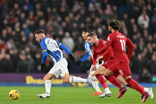 Alexis Mac Allister of Brighton evades challenges from several Liverpool players.