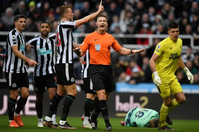 Newcastle players surround the referee after a penalty is awarded against them.